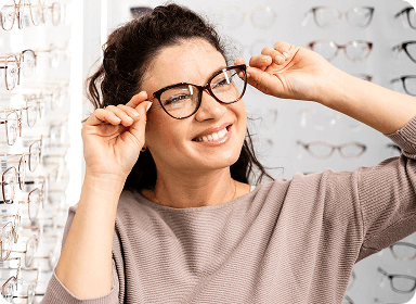Smiling woman trying on stylish brown cat-eye eyeglasses
