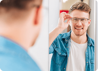 Smiling man in a denim shirt trying on modern rectangular eyeglasses