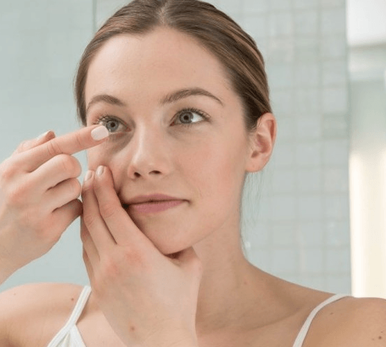 woman putting in scleral lenses on her right eye